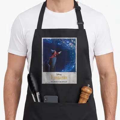 Fantasia mouse lover apron - Mickey Mouse in red robe pointing at stars above yellow Fantasia text and slogan on blue — shown on a black cotton canvas apron against a white background