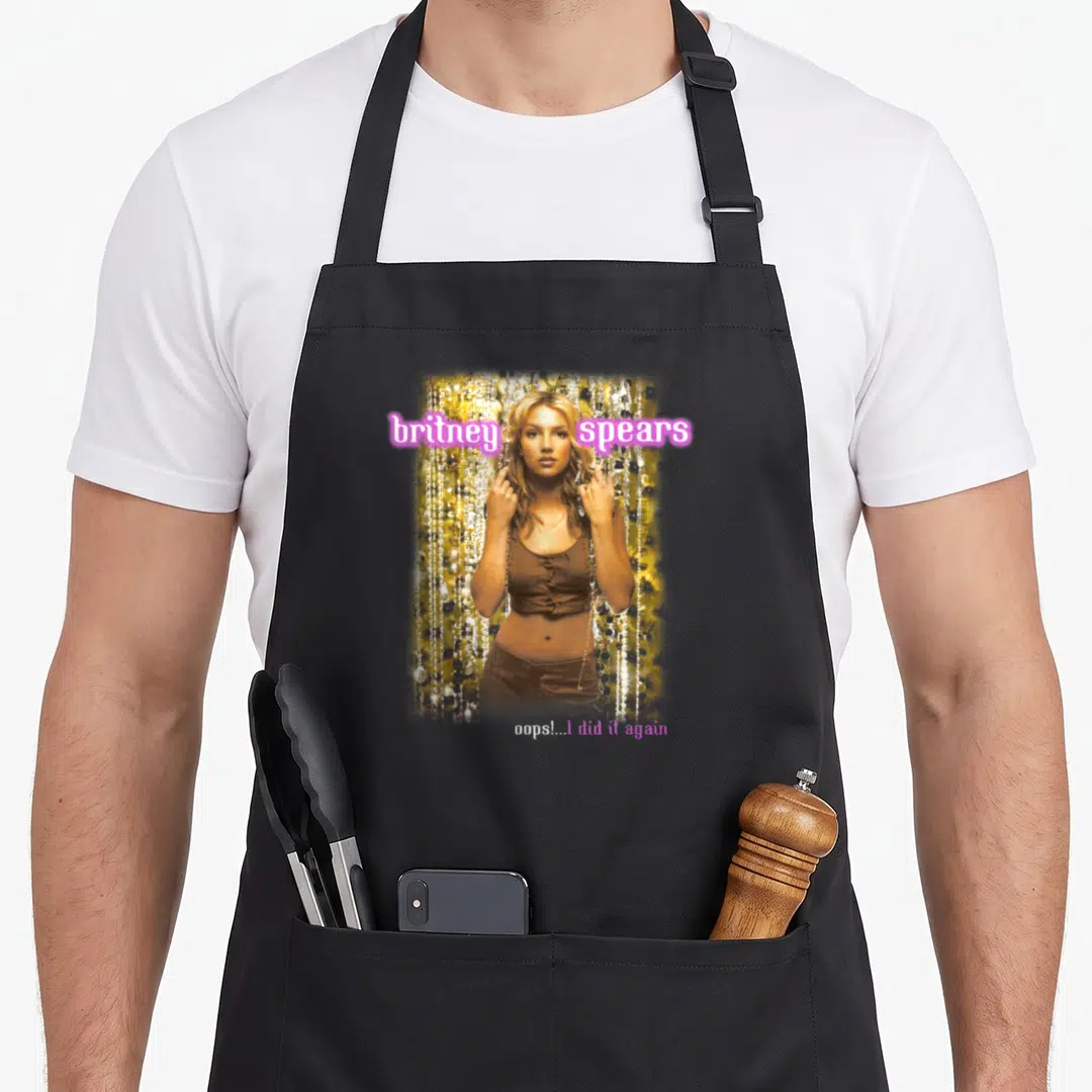 Britney i love spring apron - Photo of woman in brown top with britney spears text and oops I did it again caption — shown on a black cotton canvas apron against a white background