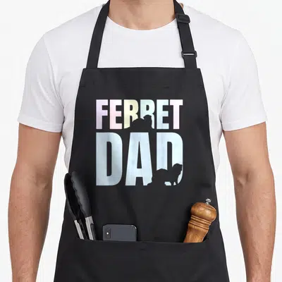 Funny animal ferret dad apron - Pastel FERRET DAD text with two grey ferret silhouettes inside letters RE and D — shown on a black cotton canvas apron against a white background