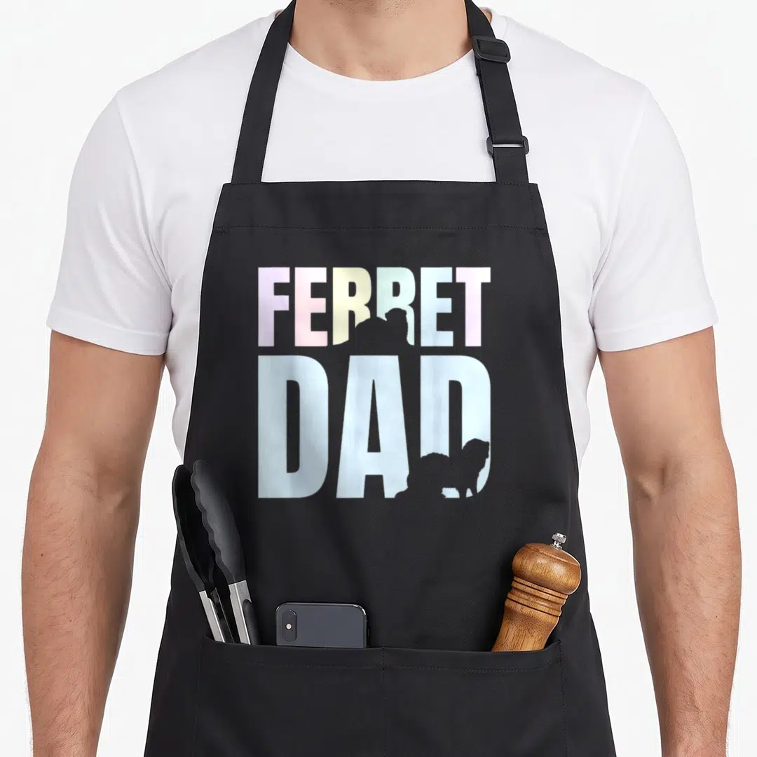 Funny animal ferret dad apron - Pastel FERRET DAD text with two grey ferret silhouettes inside letters RE and D — shown on a black cotton canvas apron against a white background