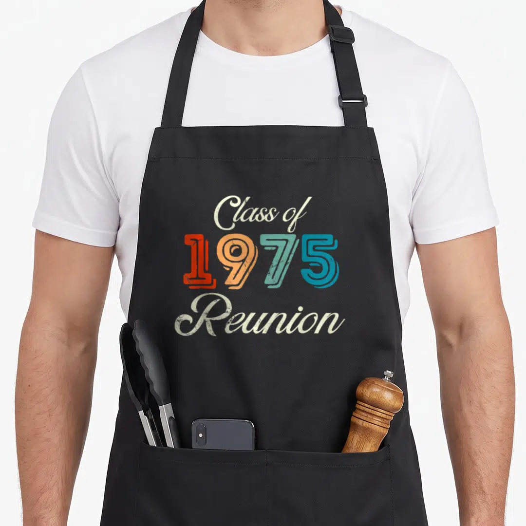 50th class reunion apron - Stacked retro typography reading Class of 1975 Reunion in cream red orange teal and blue — shown on a black cotton canvas apron against a white background