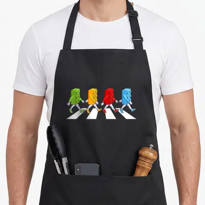 Toddler grill master apron - Four colorful toy bricks with arms and legs walking on a white crosswalk — shown on a black cotton canvas apron against a white background