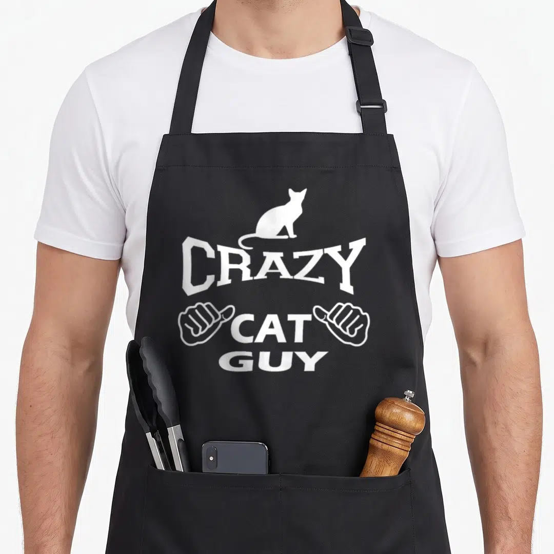 Pet black cat aprons - White line art of a cat sitting on the word crazy flanked by two thumbs up hands — shown on a black cotton canvas apron against a white background