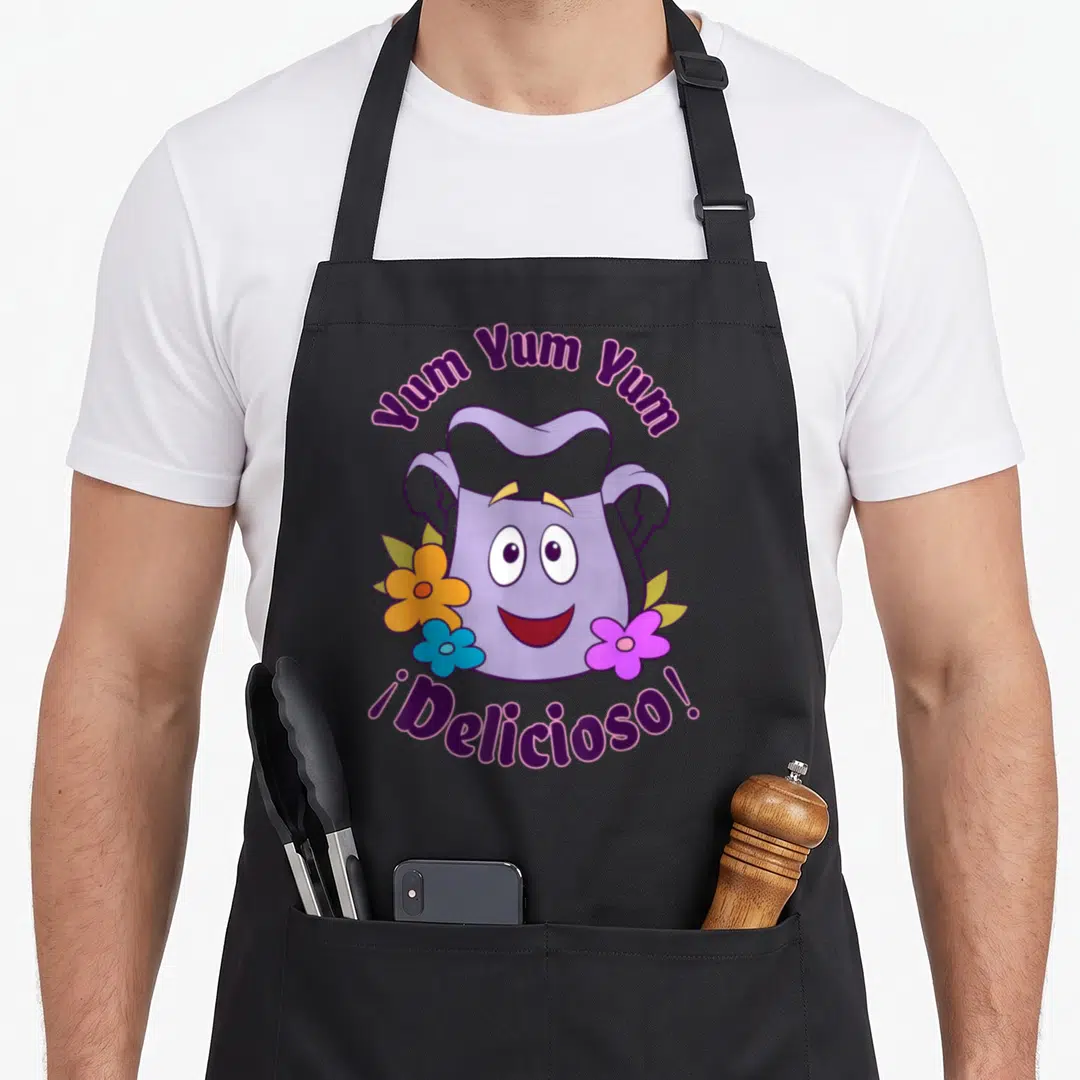 Dora backpack apron - Smiling purple bag character with Yum Yum Yum text and three colored flowers — shown on a black cotton canvas apron against a white background