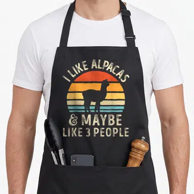 Alpacas alpaca apron - Retro striped sun with alpaca silhouette and text I like alpacas maybe like 3 people — shown on a black cotton canvas apron against a white background