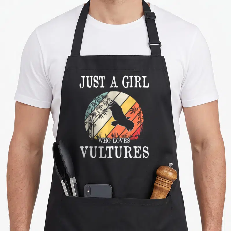 Funny vulture lover apron - Retro vulture silhouette inside a multi-colored sun circle with bamboo and white text — shown on a black cotton canvas apron against a white background