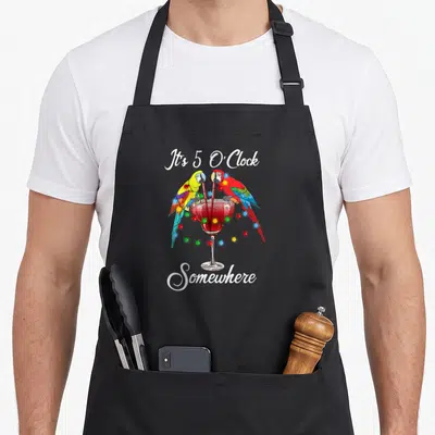 Drinking crazy parrot lady apron - Two parrots flank a red cocktail glass with colorful lights and white script text — shown on a black cotton canvas apron against a white background
