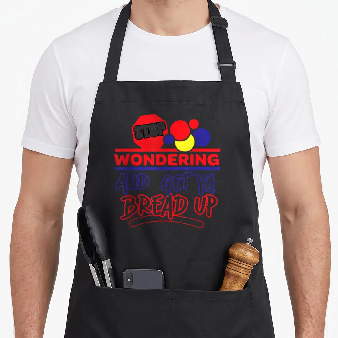 Stop bread apron - Red stop sign and stacked text reading Stop Wondering and Get Ya Bread Up with blue yellow and black — shown on a black cotton canvas apron against a white background