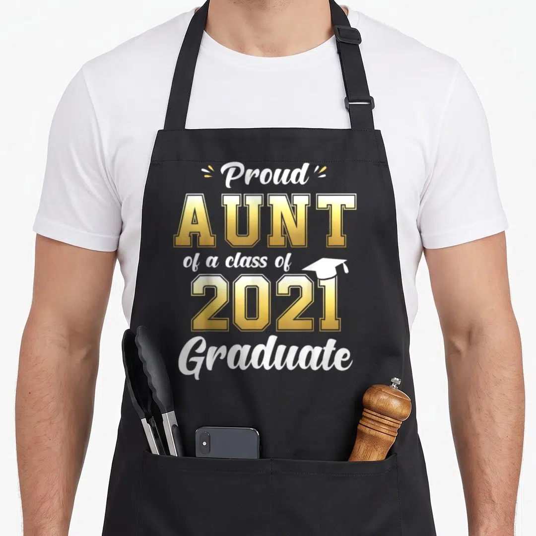 Aunt class funny apron - Proud Aunt of a class of 2021 Graduate text with small cap icon in white and gold — shown on a black cotton canvas apron against a white background