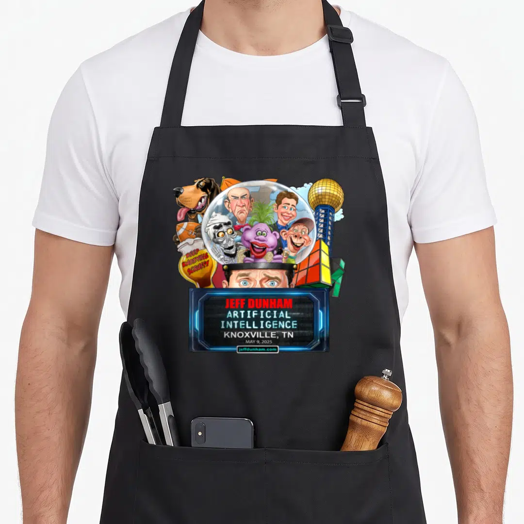 Jeff knoxville apron - Jeff Dunham puppets in dome with Keep Knoxville Scruffy sign and event text — shown on a black cotton canvas apron against a white background