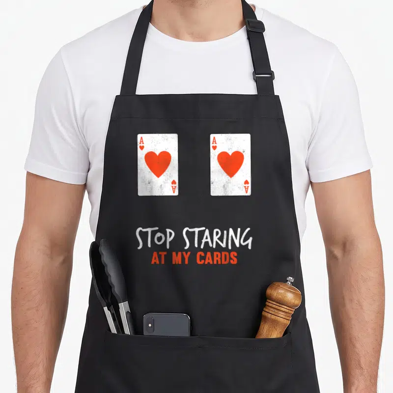 Stop poker apron - Two Ace of Hearts cards with white and orange text saying stop staring at my cards — shown on a black cotton canvas apron against a white background