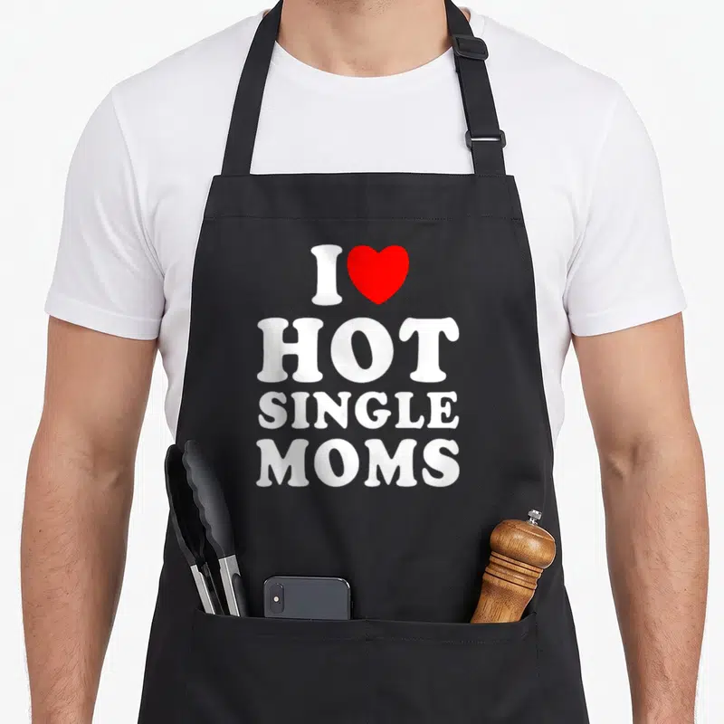 Single christmas apron - White text I HOT SINGLE MOMS with a red heart symbol on grey background — shown on a black cotton canvas apron against a white background