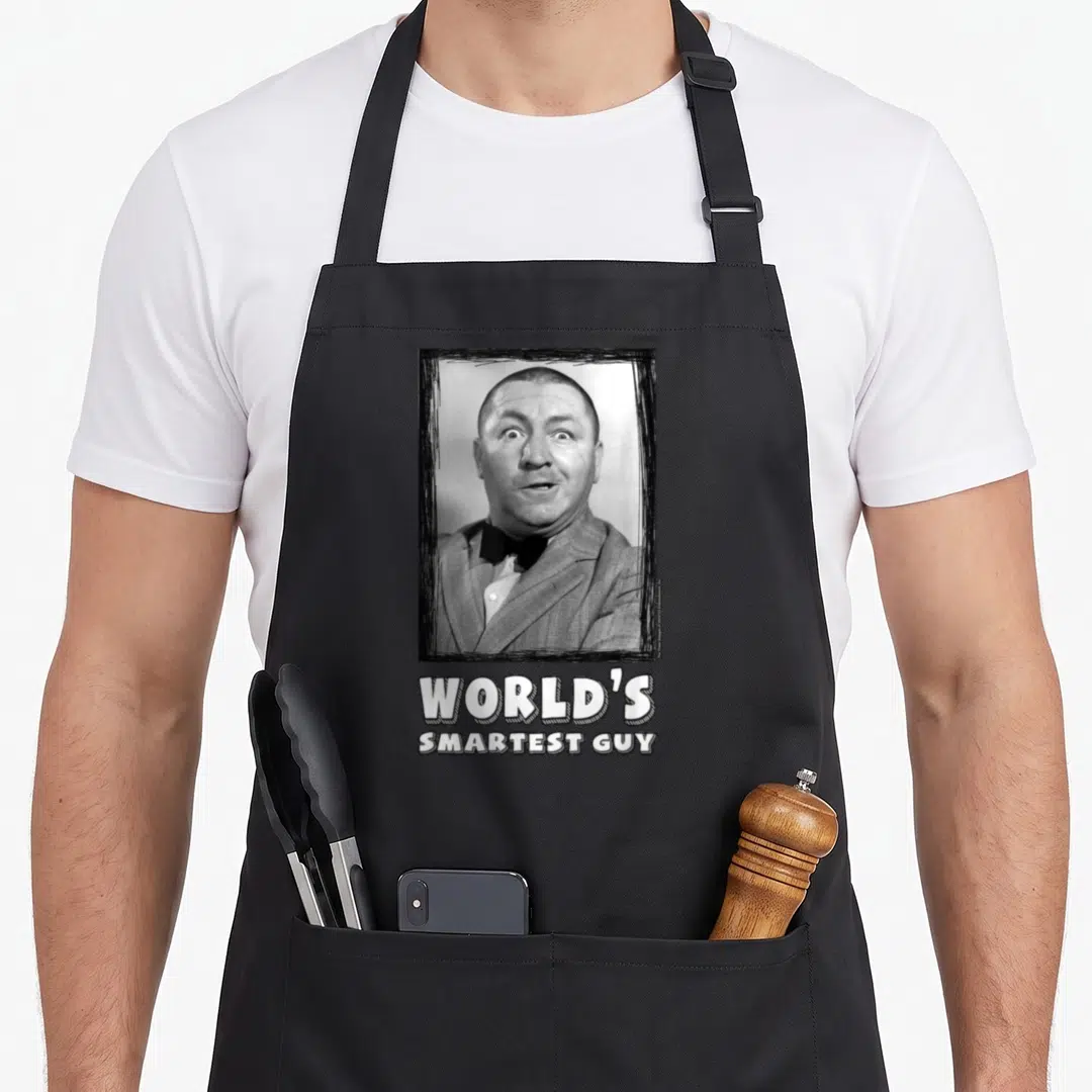 Curly three stooges apron - Grayscale man portrait in black frame above white text reading WORLD'S SMARTEST GUY — shown on a black cotton canvas apron against a white background