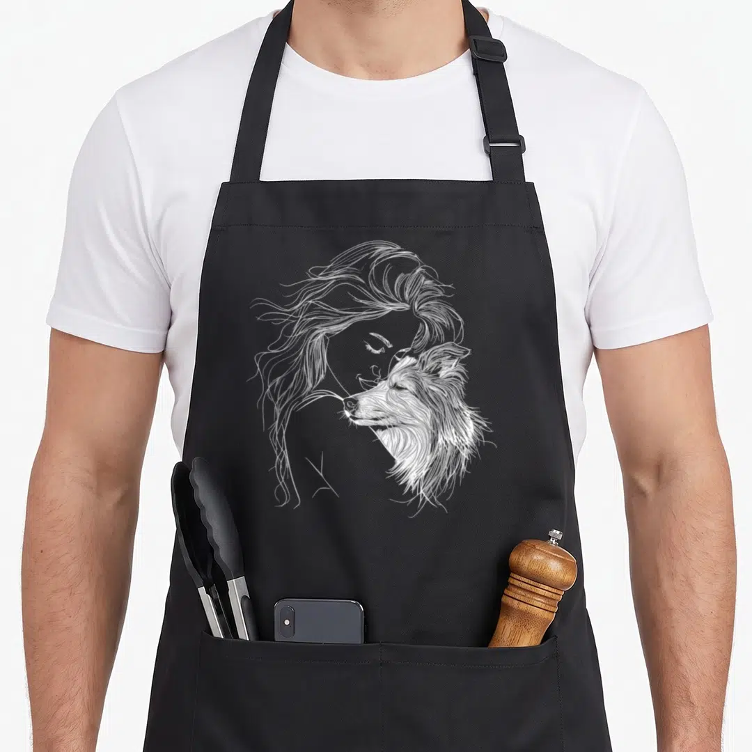 Shetland mother's day aprons - White line art of woman profile leaning against a Shetland Sheepdog — shown on a black cotton canvas apron against a white background