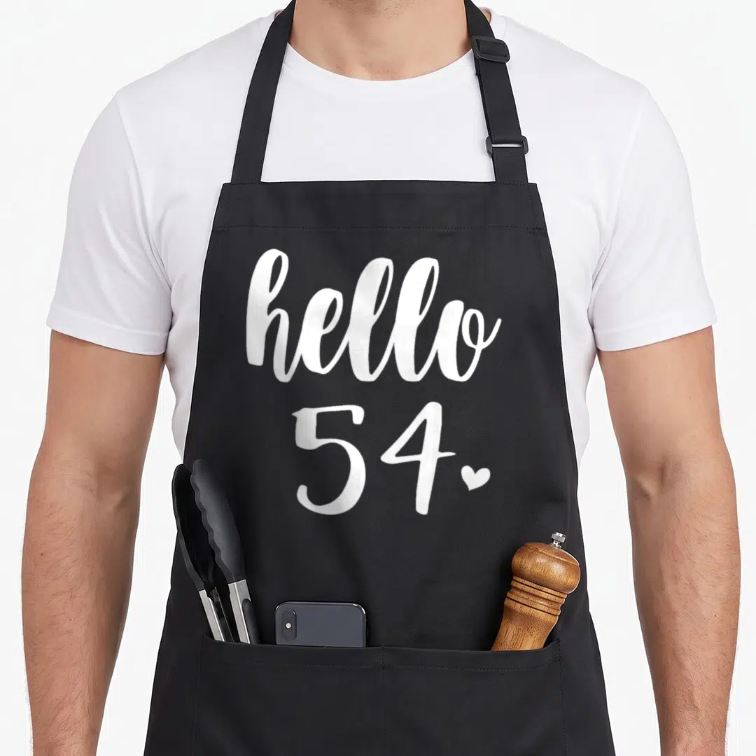 Fifty four birthday apron - Stacked white hello 54 typography with small heart on grey background — shown on a black cotton canvas apron against a white background