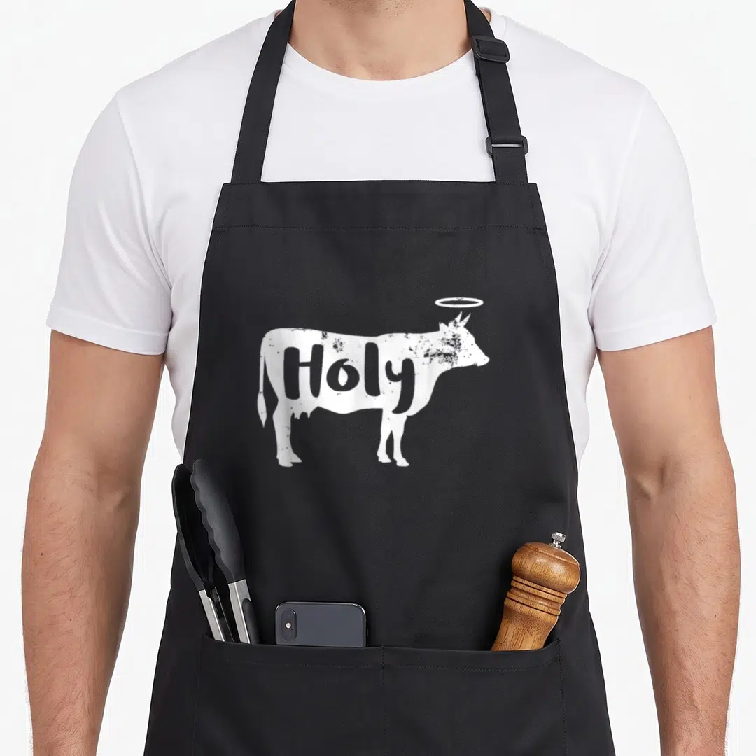 Holy farmer apron - Distressed white cow silhouette with halo and Holy text in negative space — shown on a black cotton canvas apron against a white background