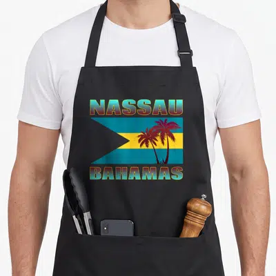Proud bahamian pride apron - Retro Nassau flag with blue yellow red stripes and two dark palm trees on right side — shown on a black cotton canvas apron against a white background