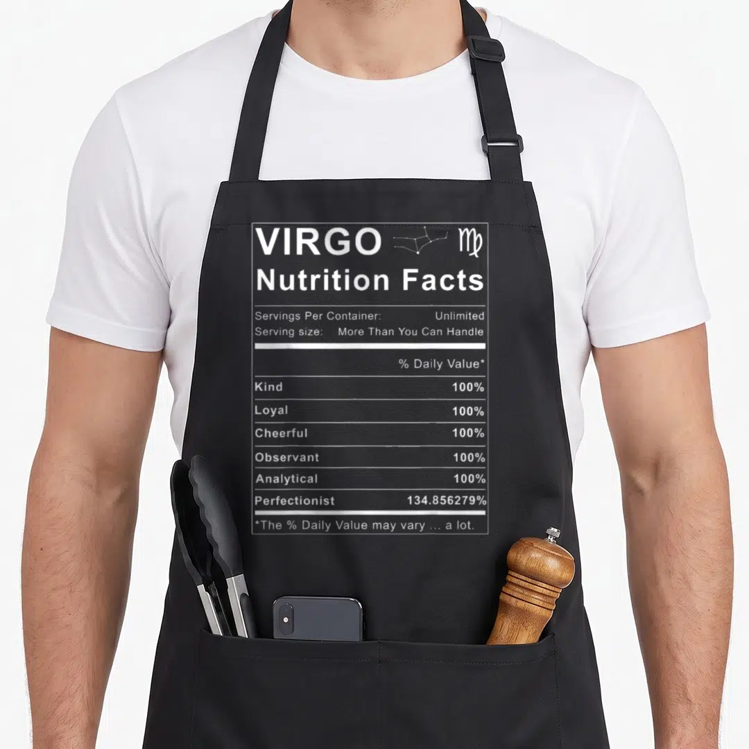 Nutrition birthday apron - White nutrition facts label print listing Virgo traits and sarcasm — shown on a black cotton canvas apron against a white background