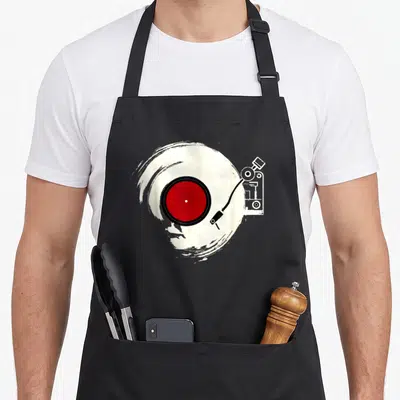 Player vinyl apron - Red vinyl record on white brush stroke with white tonearm outline — shown on a black cotton canvas apron against a white background