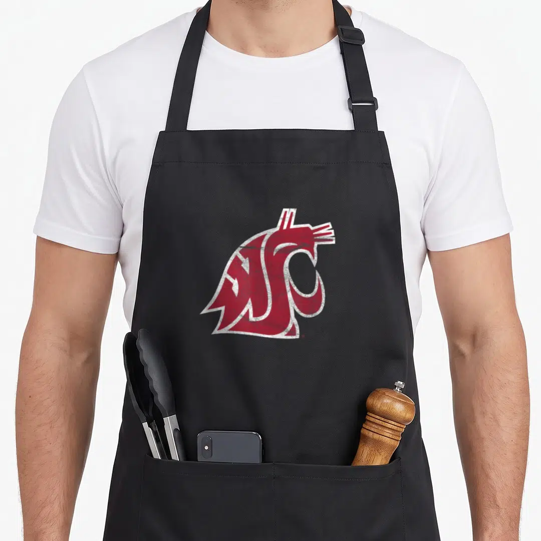 Cougar distressed apron - Crimson red cougar head logo with white outline and distressed texture — shown on a black cotton canvas apron against a white background