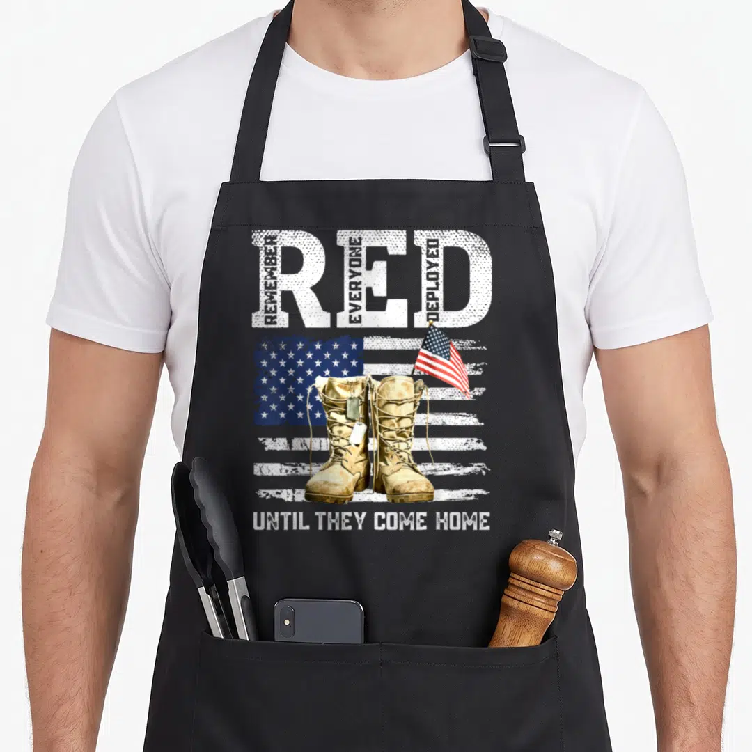 Friday force mom apron - Tan boots with dog tags in front of distressed flag under large RED text with vertical words — shown on a black cotton canvas apron against a white background
