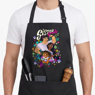Mirabel sister goals apron - Three sisters stacked vertically under arched Sister goals text with purple, yellow, pink — shown on a black cotton canvas apron against a white background