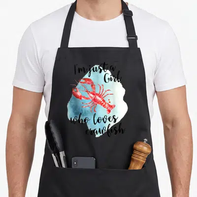 Crawfish boil cajun aprons - Red watercolor crawfish on blue splash with text I'm just a Girl who loves crawfish — shown on a black cotton canvas apron against a white background