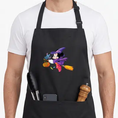 Flying halloween witch apron - Cartoon mouse in purple witch hat on broom with blue bat and pumpkin — shown on a black cotton canvas apron against a white background
