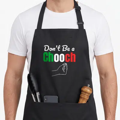 Italian chooch italy apron - Stacked text Don't Be a Chooch with clasped hands line drawing — shown on a black cotton canvas apron against a white background