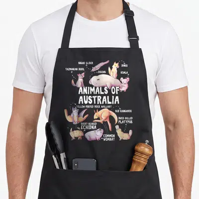 Educational australian apron - Cartoon kangaroo, koala, and platypus with labels pointing to each animal in pastel — shown on a black cotton canvas apron against a white background