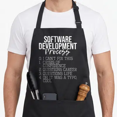 Software coder apron - White text listing Software Development Process steps including Crisis of Confidence and Oh It — shown on a black cotton canvas apron against a white background