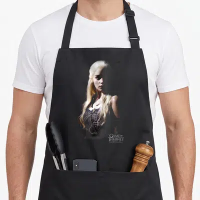Daenery game aprons - Photo portrait of a blonde woman in blue and gold with GAME OF THRONES logo text in the bottom — shown on a black cotton canvas apron against a white background