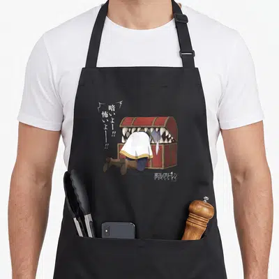 Frieren anime apron - Character stuck in red mimic chest with sharp teeth and vertical Japanese text on grey background — shown on a black cotton canvas apron against a white background