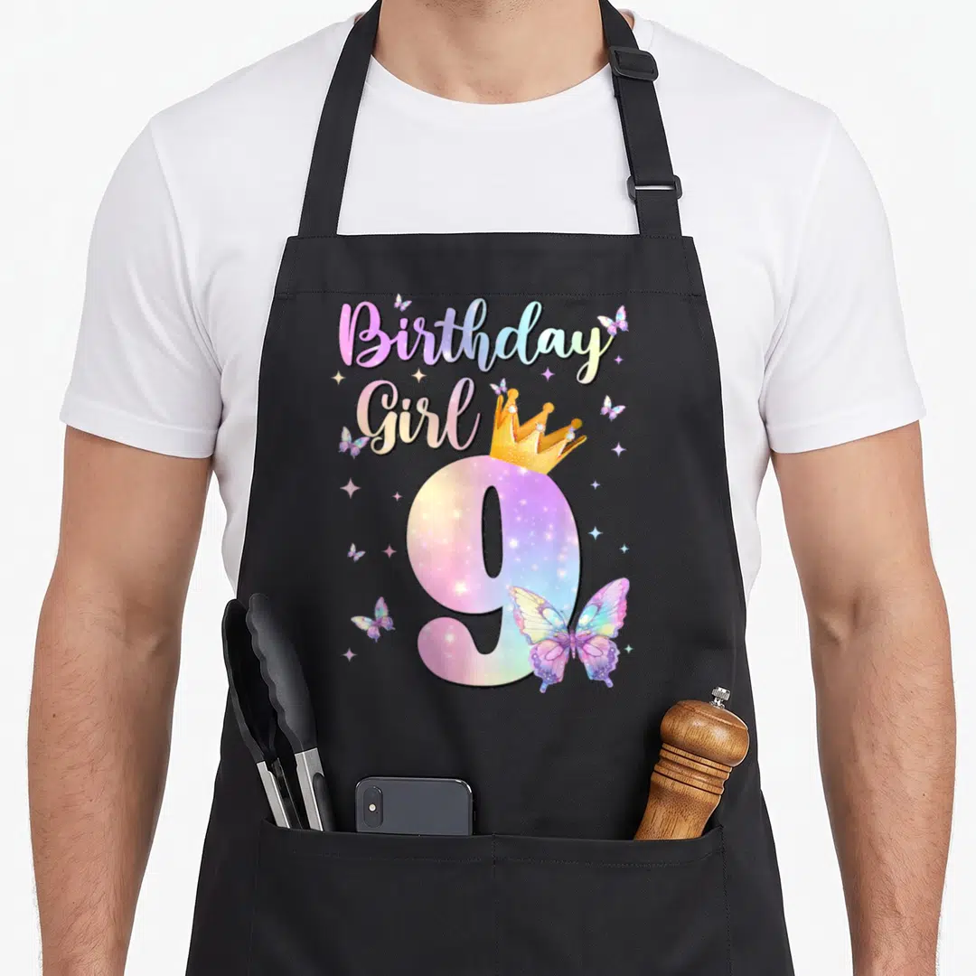 Theme butterfly aprons - Birthday Girl 9 with crown, butterflies, stars in purple pink yellow blue cartoon art — shown on a black cotton canvas apron against a white background