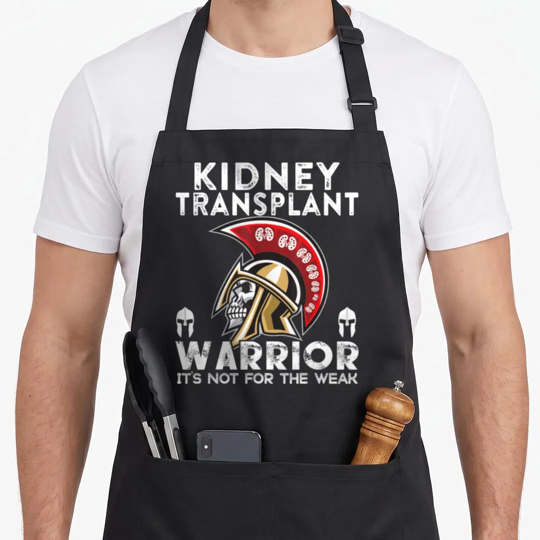 Kidney warrior transplant awareness apron - Distressed skull in Spartan helmet with kidney icons and warrior text — shown on a black cotton canvas apron against a white background