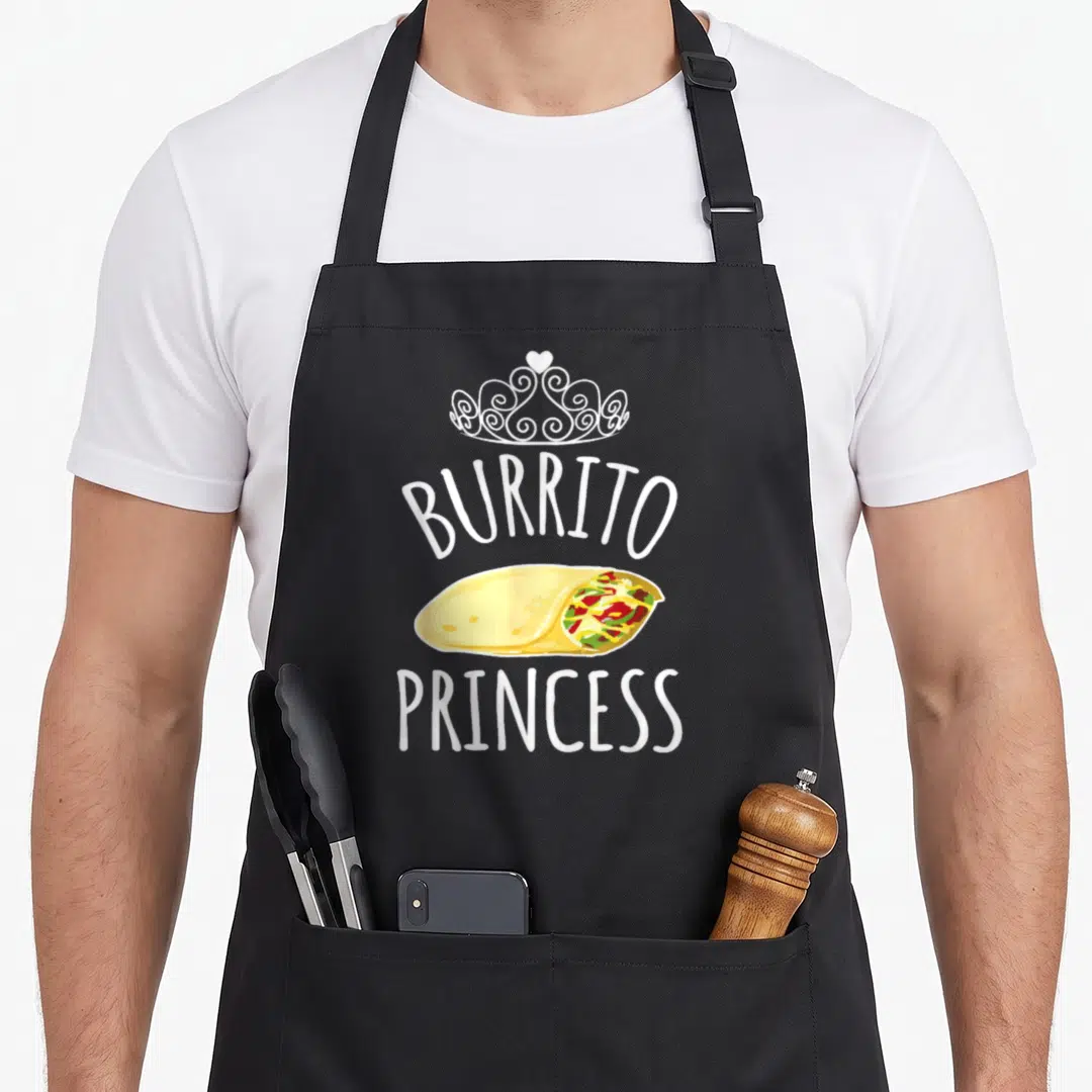 Burrito princess apron - White tiara and text surrounding a yellow burrito with red and green filling — shown on a black cotton canvas apron against a white background