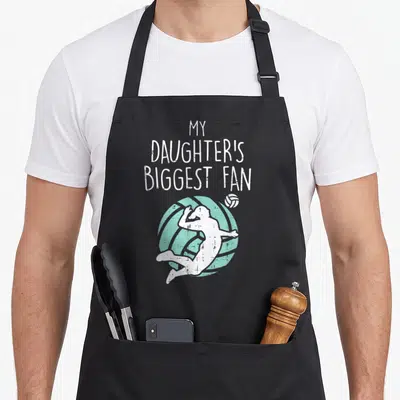 Biggest mom daughter apron - My Daughter's Biggest Fan text with jumping volleyball player silhouette in white — shown on a black cotton canvas apron against a white background