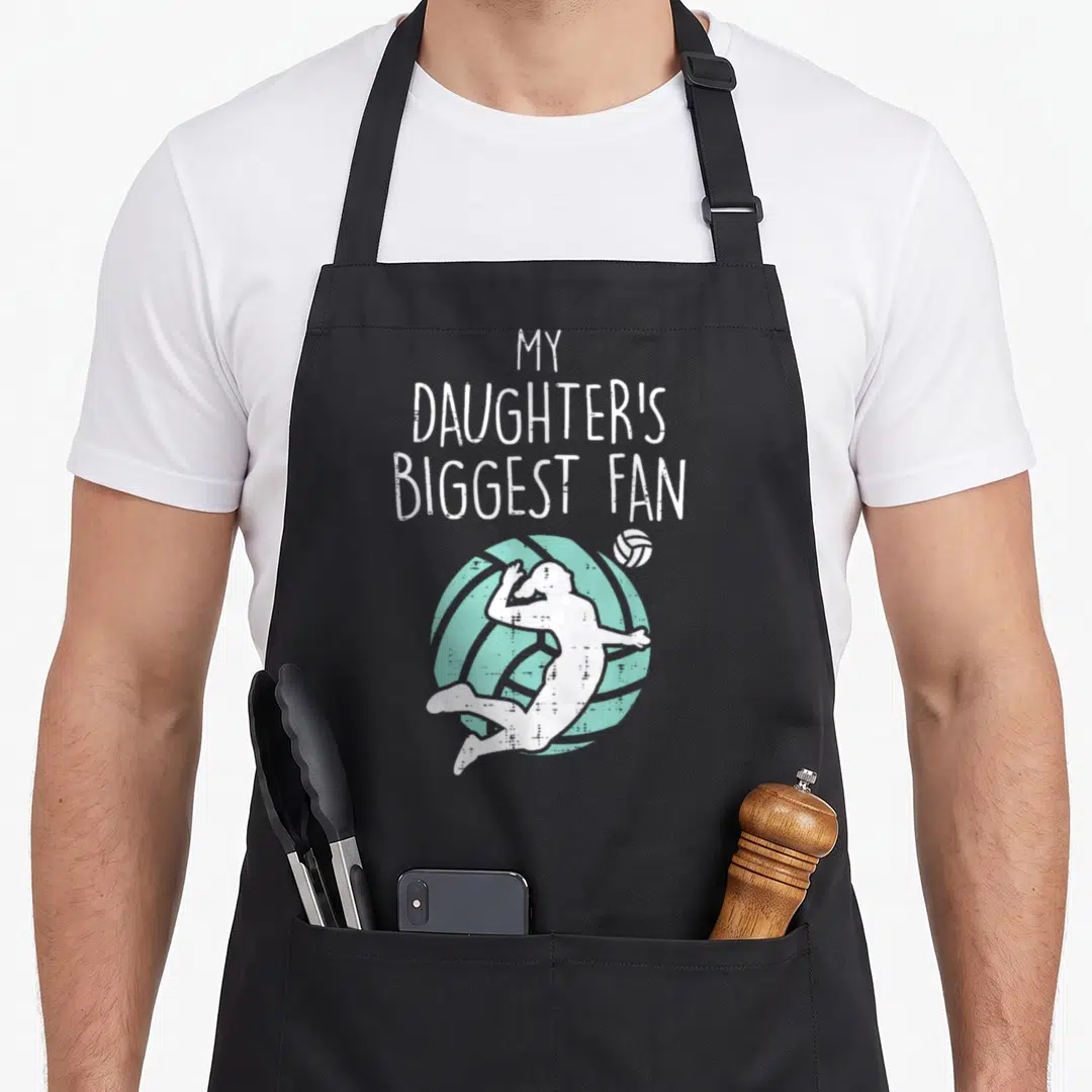 Biggest mom daughter apron - My Daughter's Biggest Fan text with jumping volleyball player silhouette in white — shown on a black cotton canvas apron against a white background