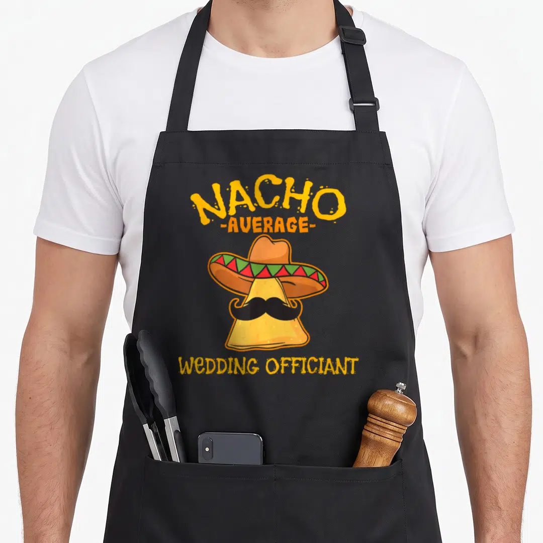 Average mexican apron - Cartoon nacho chip wearing sombrero and mustache with stacked text NACHO AVERAGE WEDDING — shown on a black cotton canvas apron against a white background