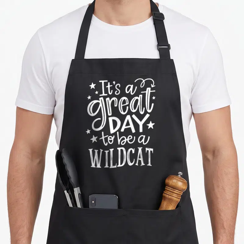 Wild cat apron - White stacked text It's a great DAY to be a WILDCAT with scattered stars — shown on a black cotton canvas apron against a white background