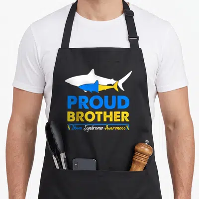 Proud chromosomes apron - Two cartoon sharks in blue yellow white above PROUD BROTHER text and awareness ribbons — shown on a black cotton canvas apron against a white background