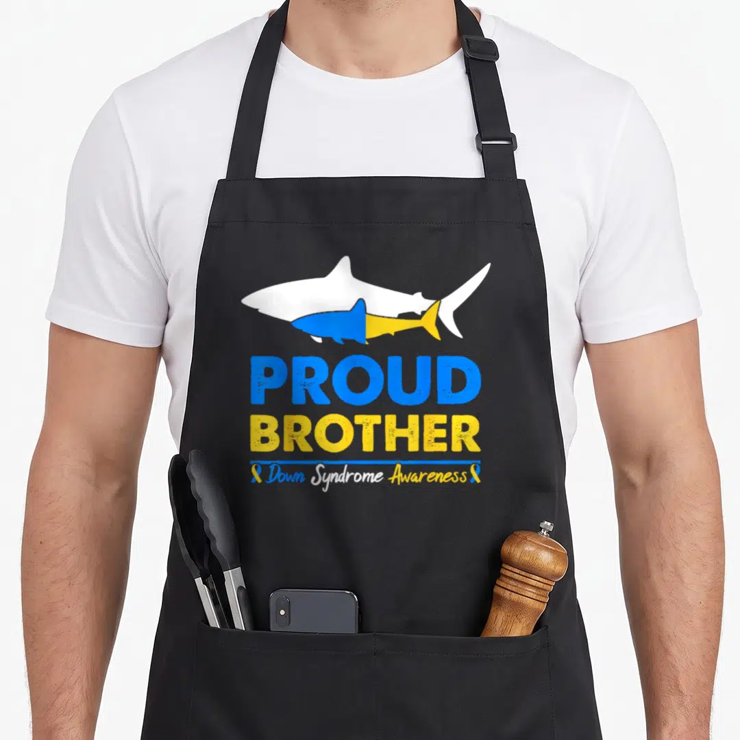 Proud chromosomes apron - Two cartoon sharks in blue yellow white above PROUD BROTHER text and awareness ribbons — shown on a black cotton canvas apron against a white background