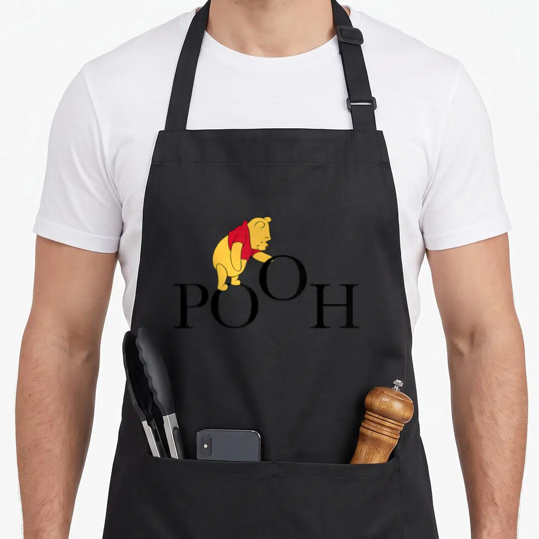 Letter novelty apron - Cartoon bear in red shirt standing on black POOH text — shown on a black cotton canvas apron against a white background