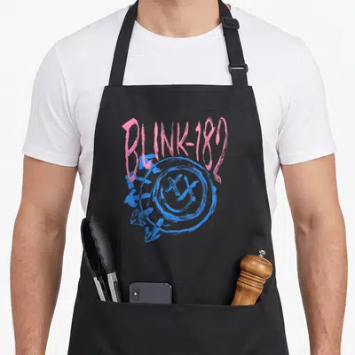 Blink black officially apron - Pink BLINK-182 text over blue scribbled smiley face with X eyes and arrows — shown on a black cotton canvas apron against a white background