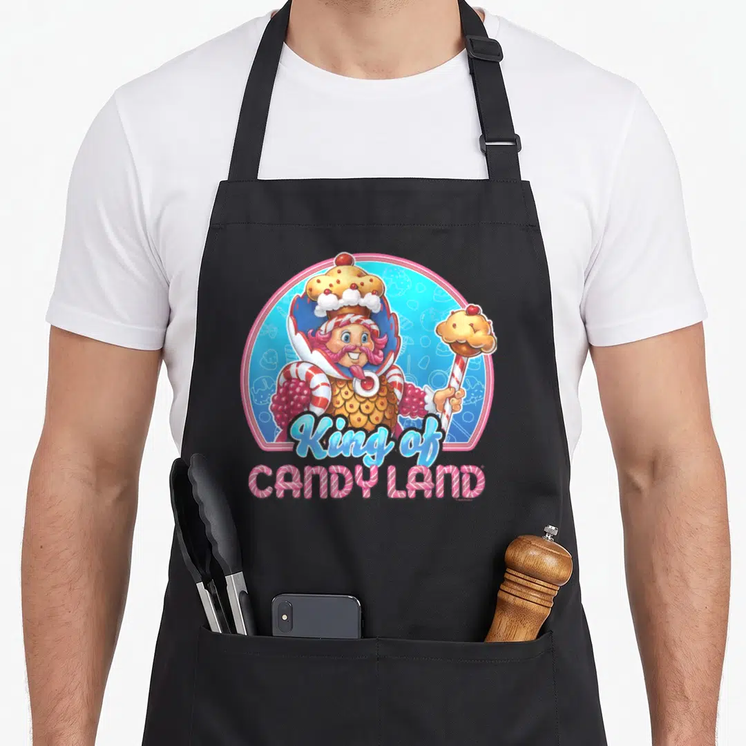 King cotton candy apron - King of Candy Land cartoon character holding cupcake scepter in blue and pink circle — shown on a black cotton canvas apron against a white background