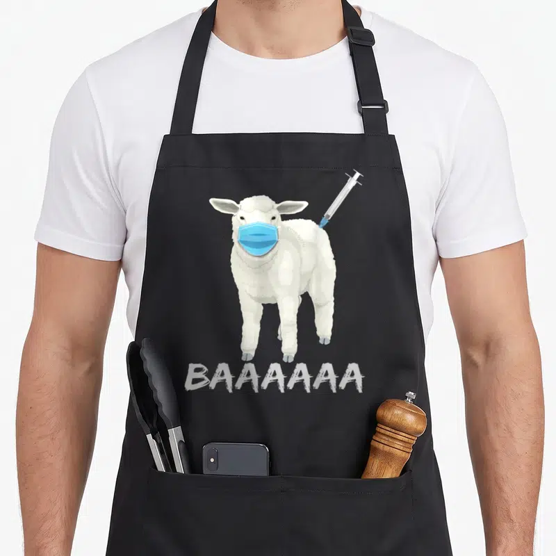 Sheeple sheep apron - Cartoon sheep wearing blue mask with syringe in back and BAAAAAAA text below — shown on a black cotton canvas apron against a white background