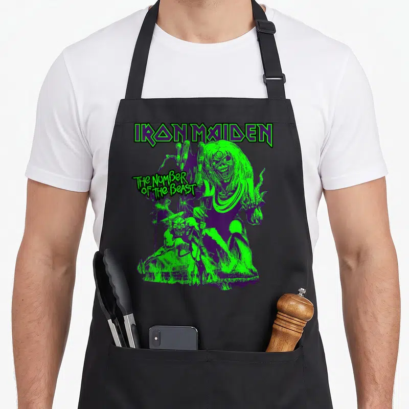 Number halloween apron - Eddie and demon figure with Iron Maiden text in green and purple distressed print — shown on a black cotton canvas apron against a white background