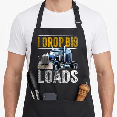 Drop semi truck apron - Blue semi-truck with I DROP BIG LOADS distressed yellow and white text — shown on a black cotton canvas apron against a white background
