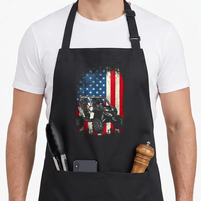 Canam imam apron - Grey UTV silhouette overlaid on distressed red white blue USA flag stars and stripes — shown on a black cotton canvas apron against a white background