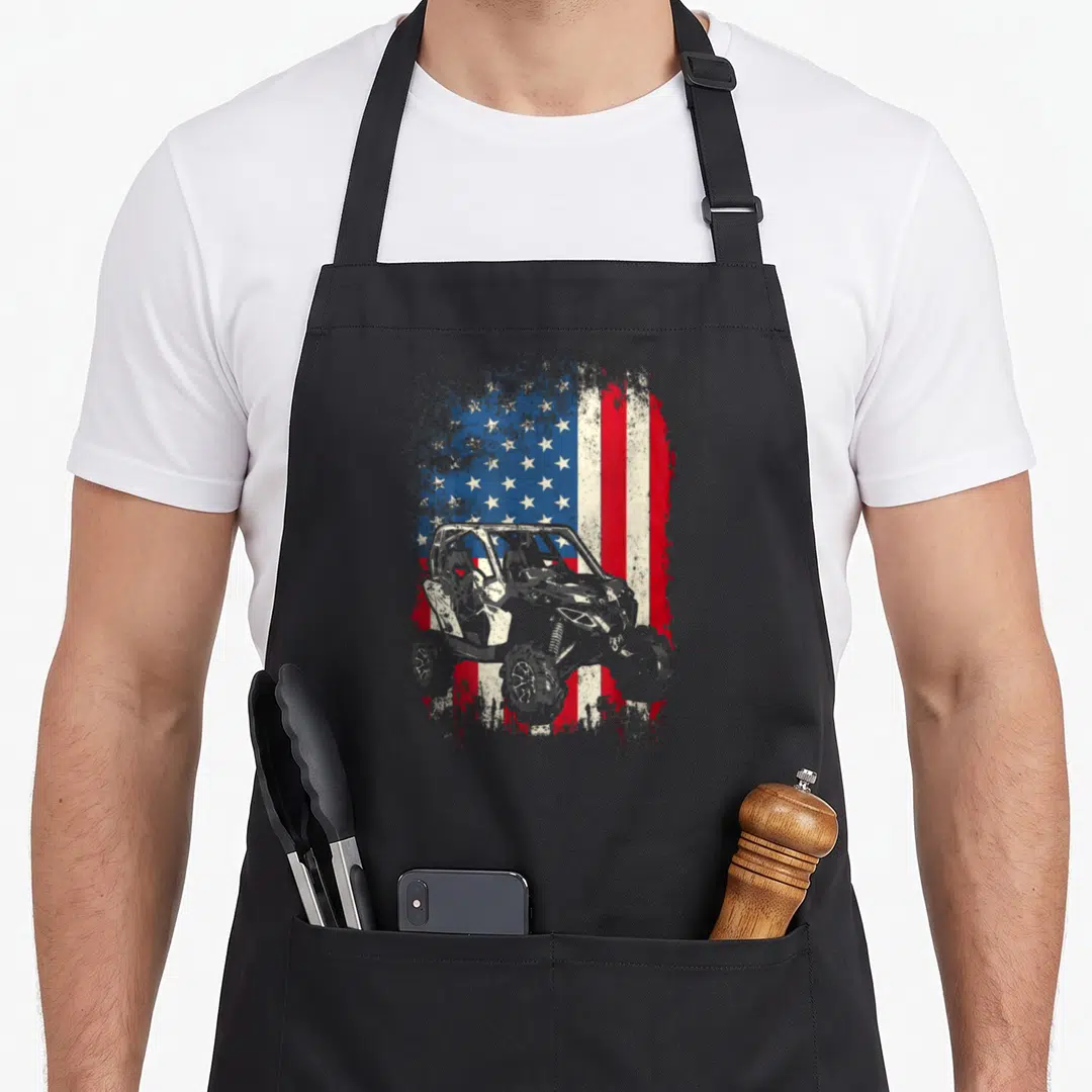 Canam imam apron - Grey UTV silhouette overlaid on distressed red white blue USA flag stars and stripes — shown on a black cotton canvas apron against a white background